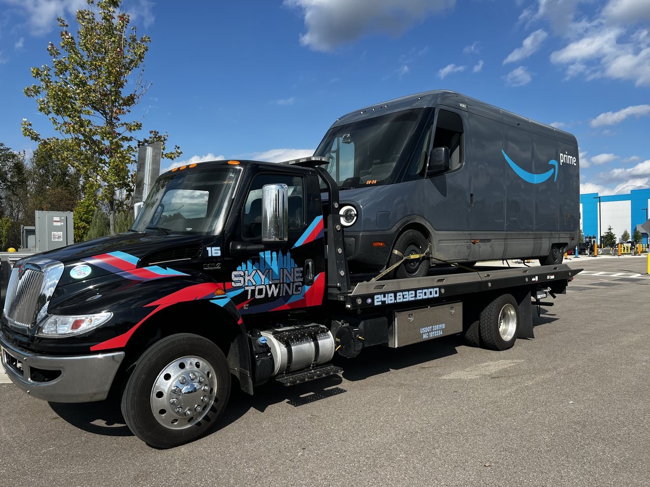 Skyline Towing flatbed tow truck carrying an electric delivery van